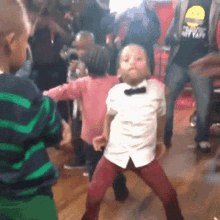 A Group Of Children Are Dancing In A Room With Adults . GIF
