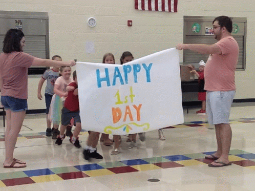 A Group Of Children Are Holding Up A Sign That Says Happy 1St Day GIF