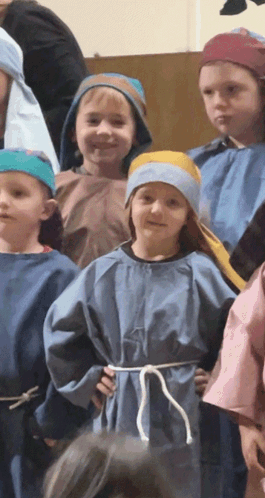 A Group Of Children Dressed In Blue Robes And Blue Hats GIF