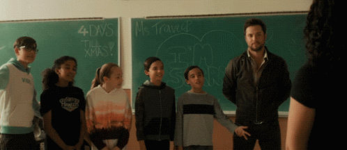 a group of children standing in front of a blackboard that says 4 days till christmas