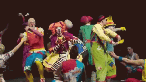 A Group Of Clowns Are Dancing Together On A Stage In Front Of A Crowd . GIF