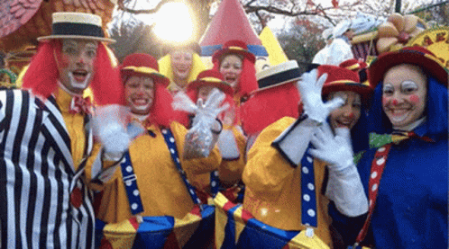 A Group Of Clowns Are Posing For A Picture And One Is Holding A Bag Of Candy GIF