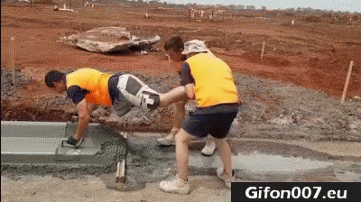 A Group Of Construction Workers Are Laying Concrete On A Road . GIF
