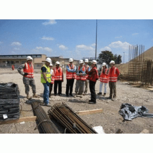 A Group Of Construction Workers Wearing Hard Hats Are Standing In A Dirt Field GIF
