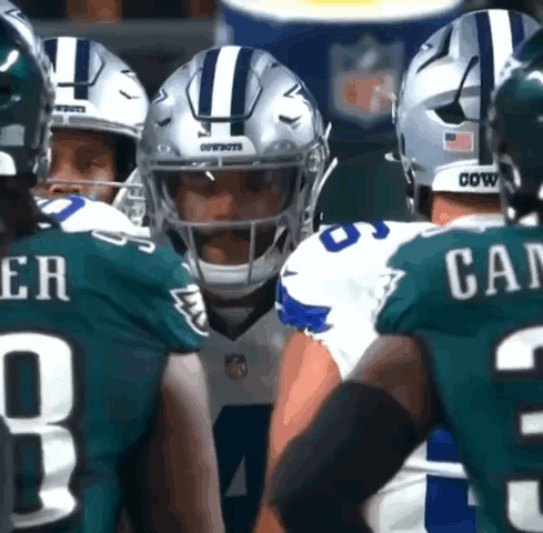 A Group Of Cowboys And Eagles Players Huddled Together GIF