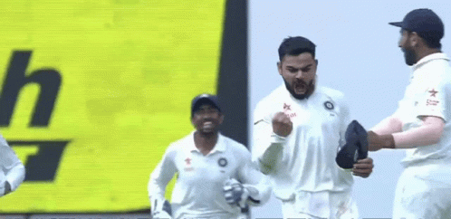 A Group Of Cricket Players Are Celebrating A Win In Front Of A Yellow Sign . GIF