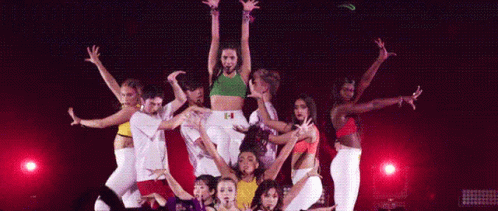 A Group Of Dancers Are Performing On A Stage With A Woman Standing In The Middle . GIF