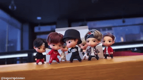 A Group Of Dolls Are Dancing Together On A Table . GIF