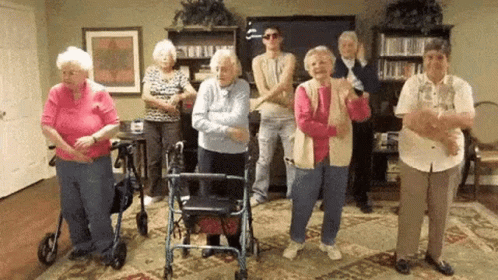A Group Of Elderly People Are Dancing In A Living Room . GIF