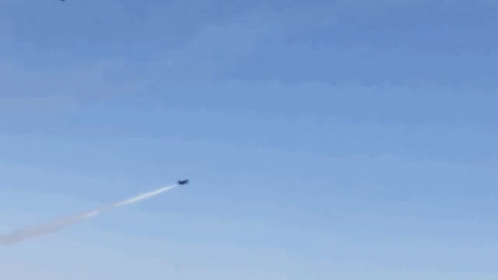 A Group Of Fighter Jets Are Flying In Formation In A Blue Sky GIF