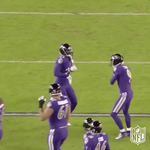 a group of football players are jumping in the air on a field during a game .