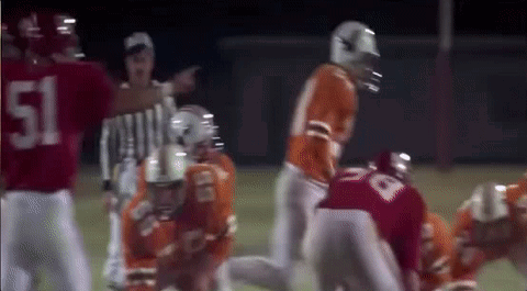A Group Of Football Players Are Playing A Game On A Field With A Referee . GIF