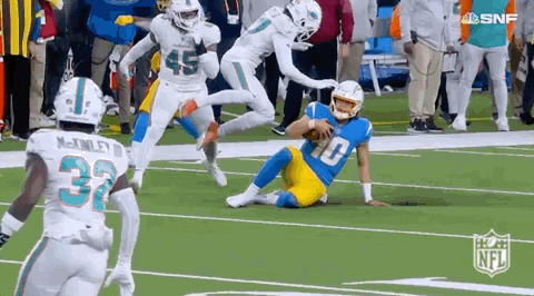 A Group Of Football Players Are Running On A Field . GIF