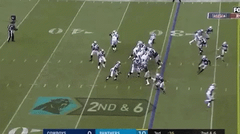 A Group Of Football Players Are Running On A Field While A Man Stands Behind Them . GIF