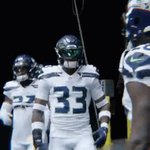 A Group Of Football Players Are Standing In A Dark Room . GIF