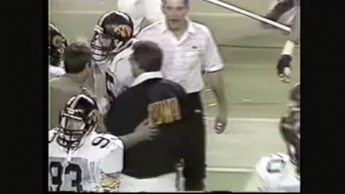 A Group Of Football Players Are Standing Next To Each Other On A Field With A Referee . GIF