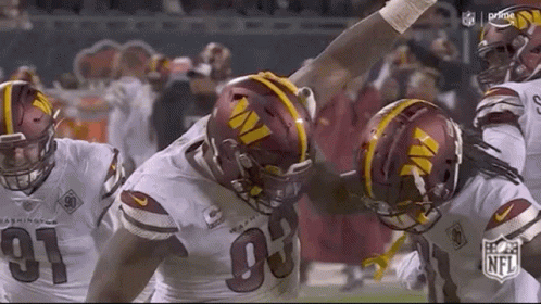 A Group Of Football Players Are Standing Next To Each Other On The Field . GIF