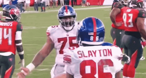 A Group Of Football Players Are Standing On A Field . GIF