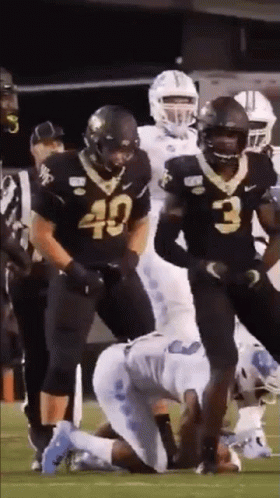 A Group Of Football Players Are Standing On A Field . GIF
