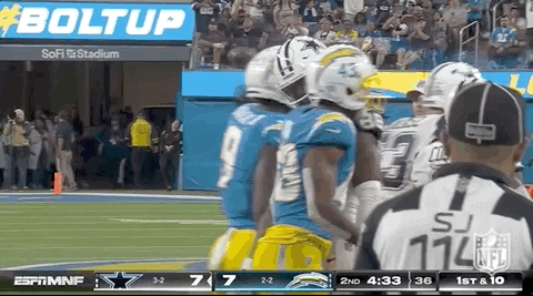A Group Of Football Players Are Standing On A Field Next To A Referee . GIF