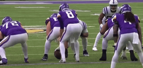 A Group Of Football Players Are Standing On A Field . GIF