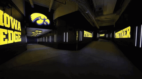 A Group Of Football Players Are Walking In A Tunnel With A Sign That Says Back In GIF
