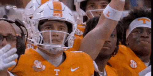 a group of football players wearing orange uniforms with the letter t on them