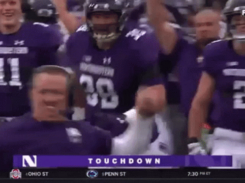 A Group Of Football Players Wearing Purple Uniforms Are Celebrating A Touchdown Against Penn State GIF