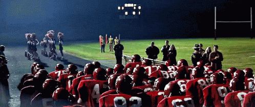 A Group Of Football Players Wearing Red Uniforms With The Number 22 On The Back Stand In Front Of A Scoreboard GIF