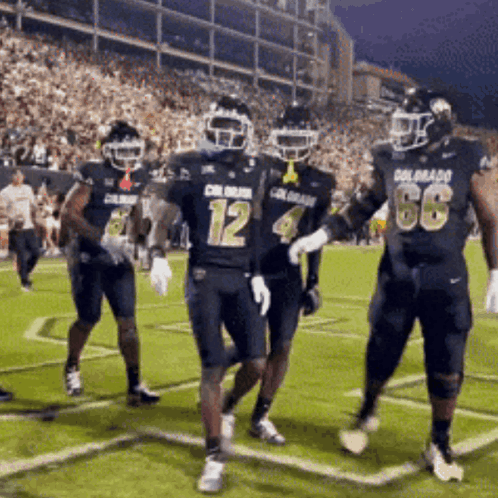 a group of football players wearing uniforms that say colorado are running on the field
