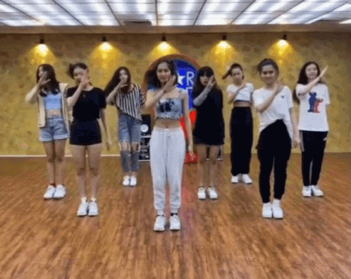 A Group Of Girls Are Dancing In A Room With A Sign That Says R. GIF