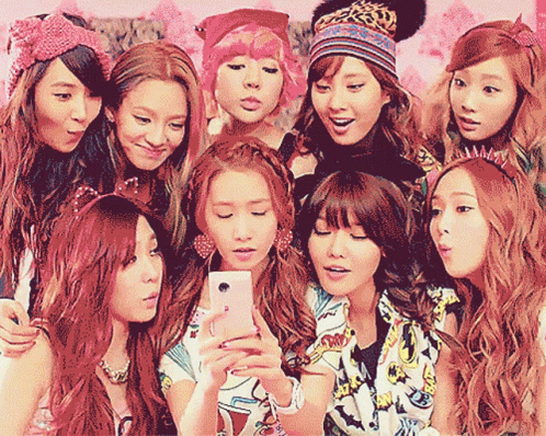 A Group Of Girls Are Posing For A Picture With One Girl Holding A Cell Phone GIF