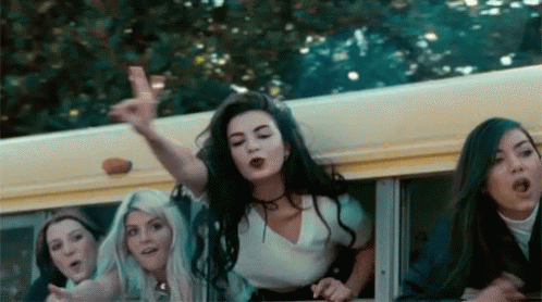 A Group Of Girls Are Riding On The Back Of A School Bus And One Girl Is Pointing At The Camera . GIF