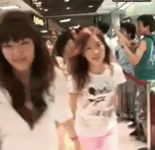 A Group Of Girls Are Standing Next To Each Other In A Crowded Room . GIF