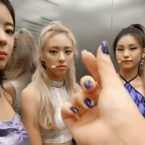 A Group Of Girls Are Standing Next To Each Other In An Elevator . One Of The Girls Is Wearing A Purple Dress . GIF