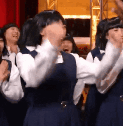 A Group Of Girls In School Uniforms Are Standing In A Room And Laughing . GIF