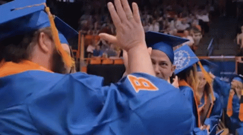a group of graduates are giving each other a high five .