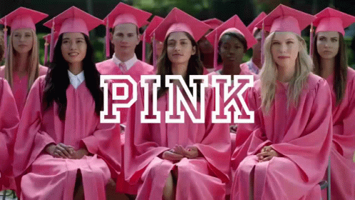 A Group Of Graduates Wearing Pink Gowns And Caps Are Sitting In A Row GIF