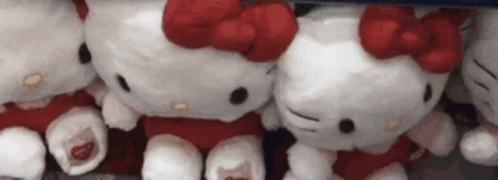 A Group Of Hello Kitty Stuffed Animals Are Sitting Next To Each Other On A Table . GIF
