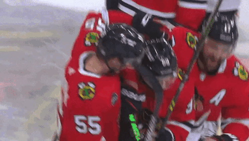 A Group Of Hockey Players Are Huddled Together On The Ice . One Of The Players Has The Number 55 On His Jersey . GIF