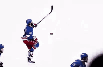 A Group Of Hockey Players Are Playing A Game On The Ice While A Referee Looks On . GIF