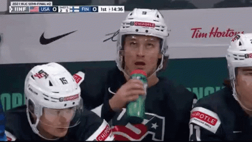 A Group Of Ice Hockey Players Are Sitting On The Bench Drinking Water . GIF