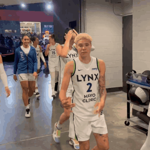 A Group Of Lynx Basketball Players Are Walking Through A Locker Room GIF