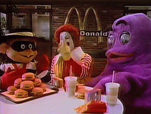 A Group Of Mcdonald 'S Mascots Are Sitting At A Table With Hamburgers And Drinks GIF