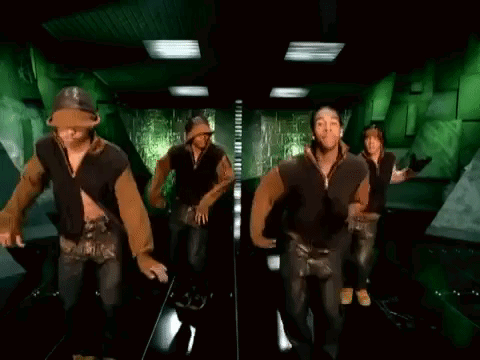 A Group Of Men And Women Are Dancing In A Hallway . GIF