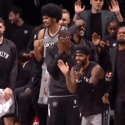 A Group Of Men Are Applauding A Basketball Player Wearing A Brooklyn Nets Jersey . GIF