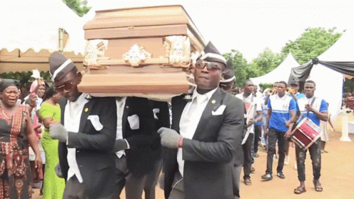 A Group Of Men Are Carrying A Coffin In A Line GIF