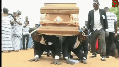 A Group Of Men Are Carrying A Wooden Coffin On Their Knees GIF