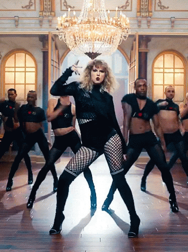 A Group Of Men Are Dancing In A Room With A Chandelier Above Them GIF