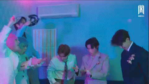 A Group Of Men Are Dancing In A Room With A Purple Light Behind Them . GIF